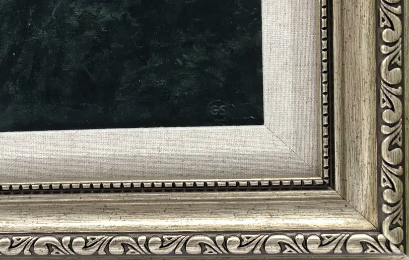 Close up of the ornate picture frame with a white linen slip, showing the dark, textured oil paint of the forested shoreline.