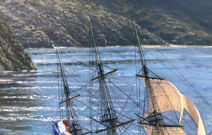 Close up of the ship's masts, rigging, and sails set against the steep, rugged, and heavily forested slopes of the New Zealand coastline.