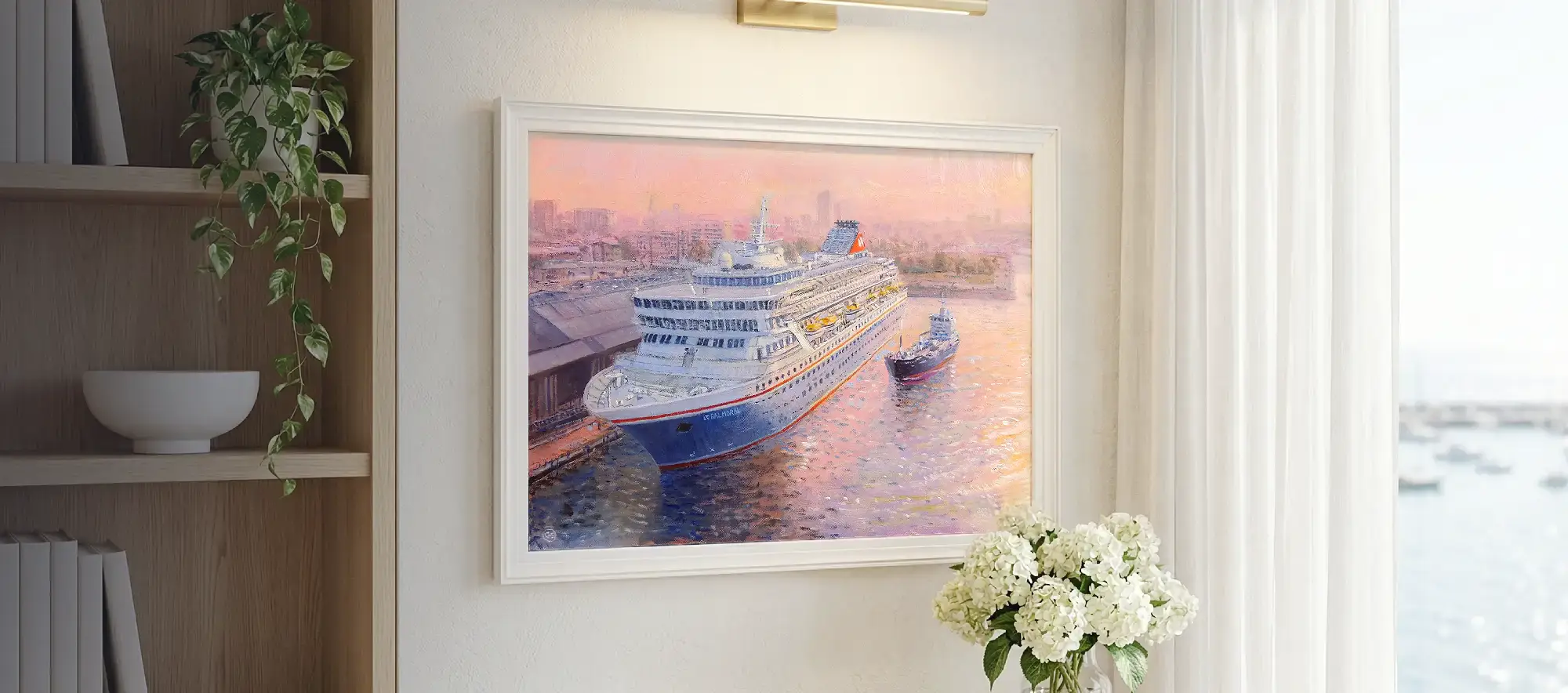 Framed painting of the cruise ship Balmoral hanging on a white wall above a light wood console table decorated with white hydrangeas.