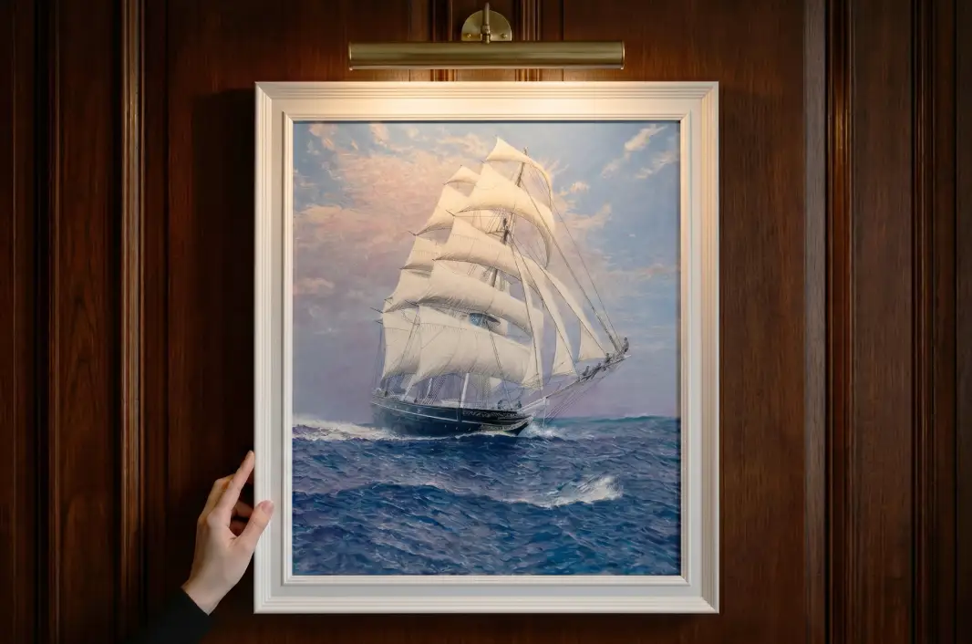 A person's hands adjusting the vertically framed painting against rich dark wooden wall panelling under a warm picture light.
