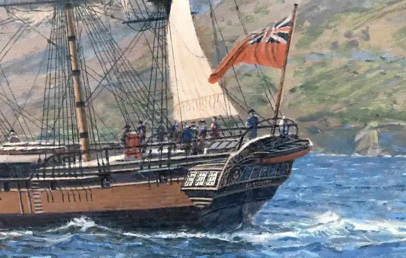 Close up of the stern and hull of HMS Discovery, showing detailed rigging and a red ensign flying at the back, set against the green Hawaiian coastline.
