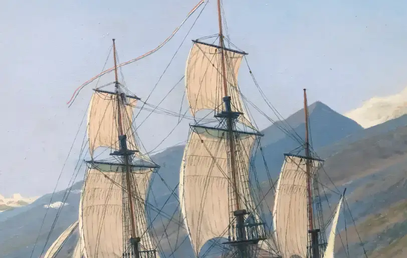 Close up of the ship's upper masts and billowing square sails against the distant volcanic mountains and blue sky.