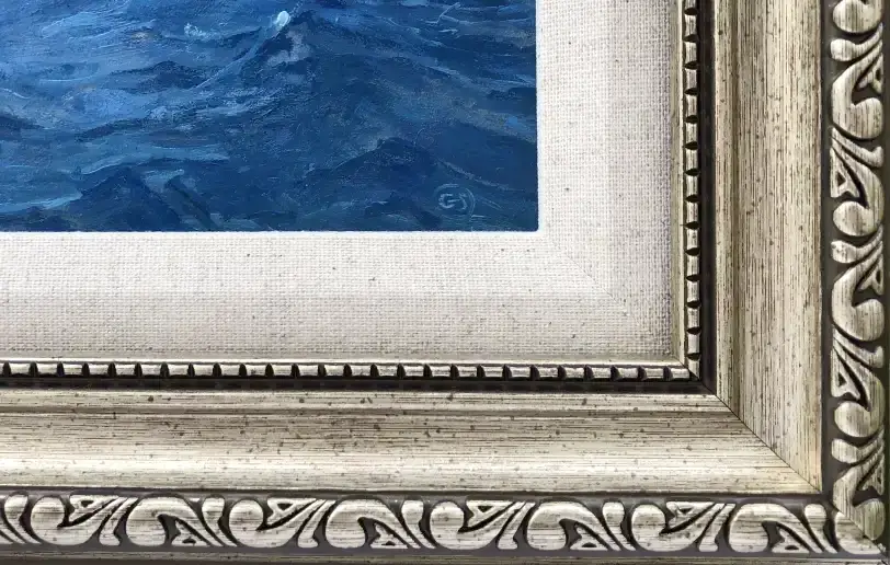 Close up of the ornate silver-toned picture frame with an inner white linen slip, contrasting with the dark blue painted water.