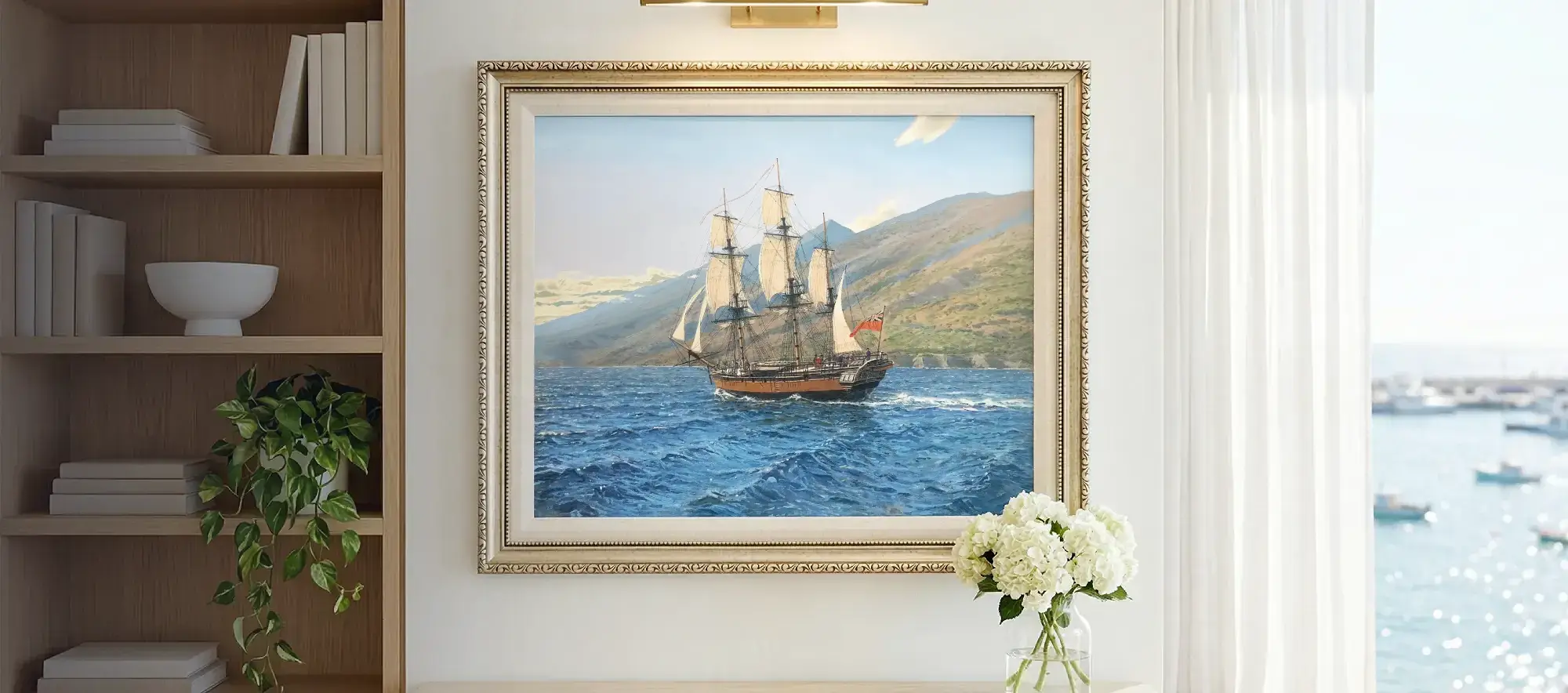 Framed painting of HMS Discovery hanging on a white wall in a bright room with a bookcase and coastal window view.