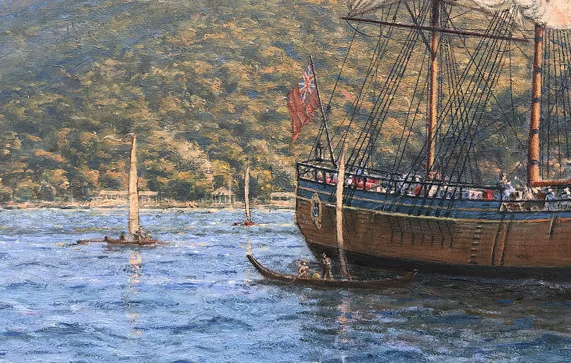 Close-up detail of HMB Endeavour's stern showing the Red Ensign flag and traditional Tahitian outrigger canoes nearby on the water.