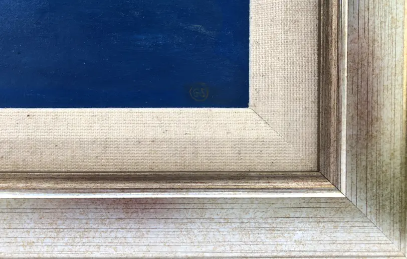 Close up of the champagne gold picture frame, the inner white linen slip, and the artist's signature over the blue ocean.