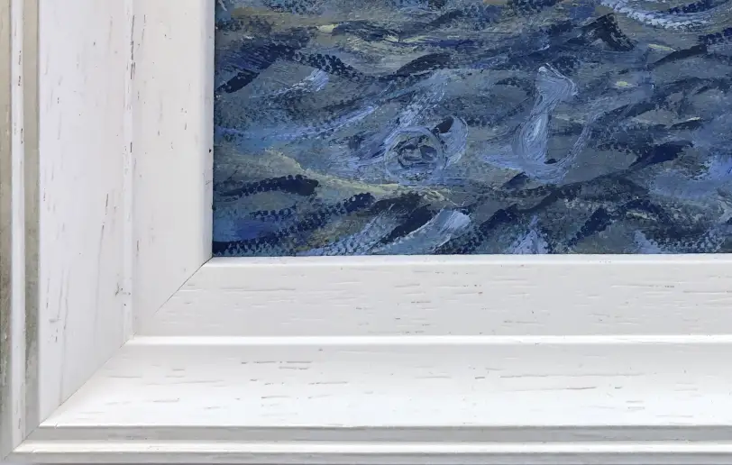 Close up of the white wood picture frame and the textured blue oil paint of the sea.