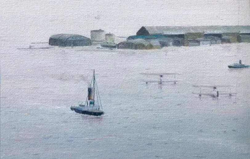 Close up of the distant coastline, showing the low-lying buildings and hangars of Calshot Spit.