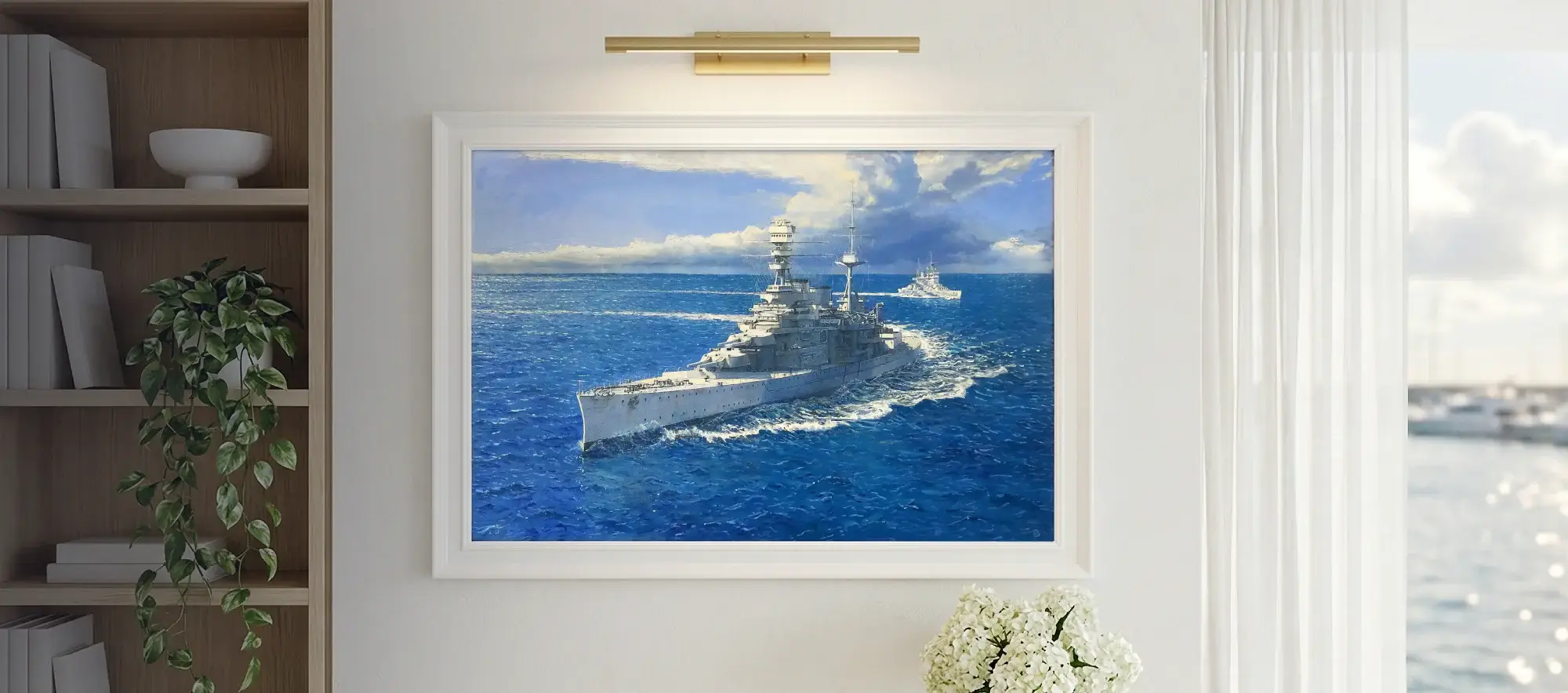 Framed painting of HMS Repulse hanging on a white wall above a light wood table with a vase of white hydrangeas, flanked by a modern bookcase.