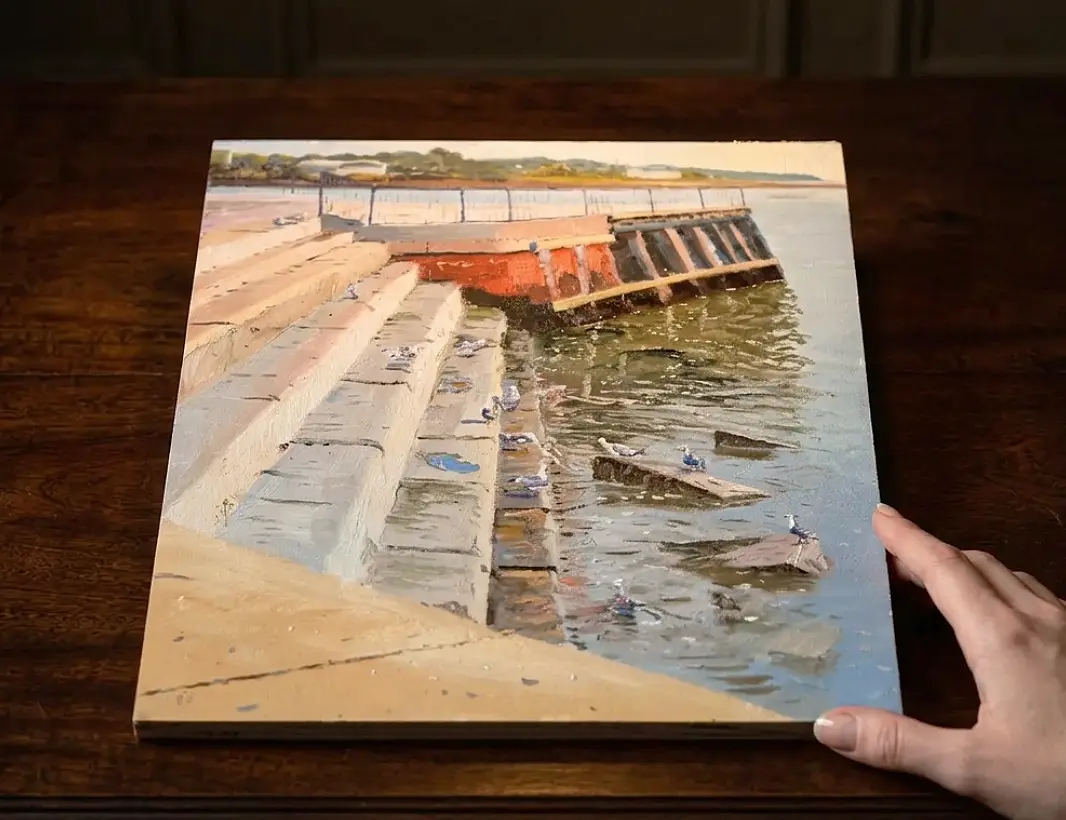 The unframed canvas held flat against a dark wooden table.