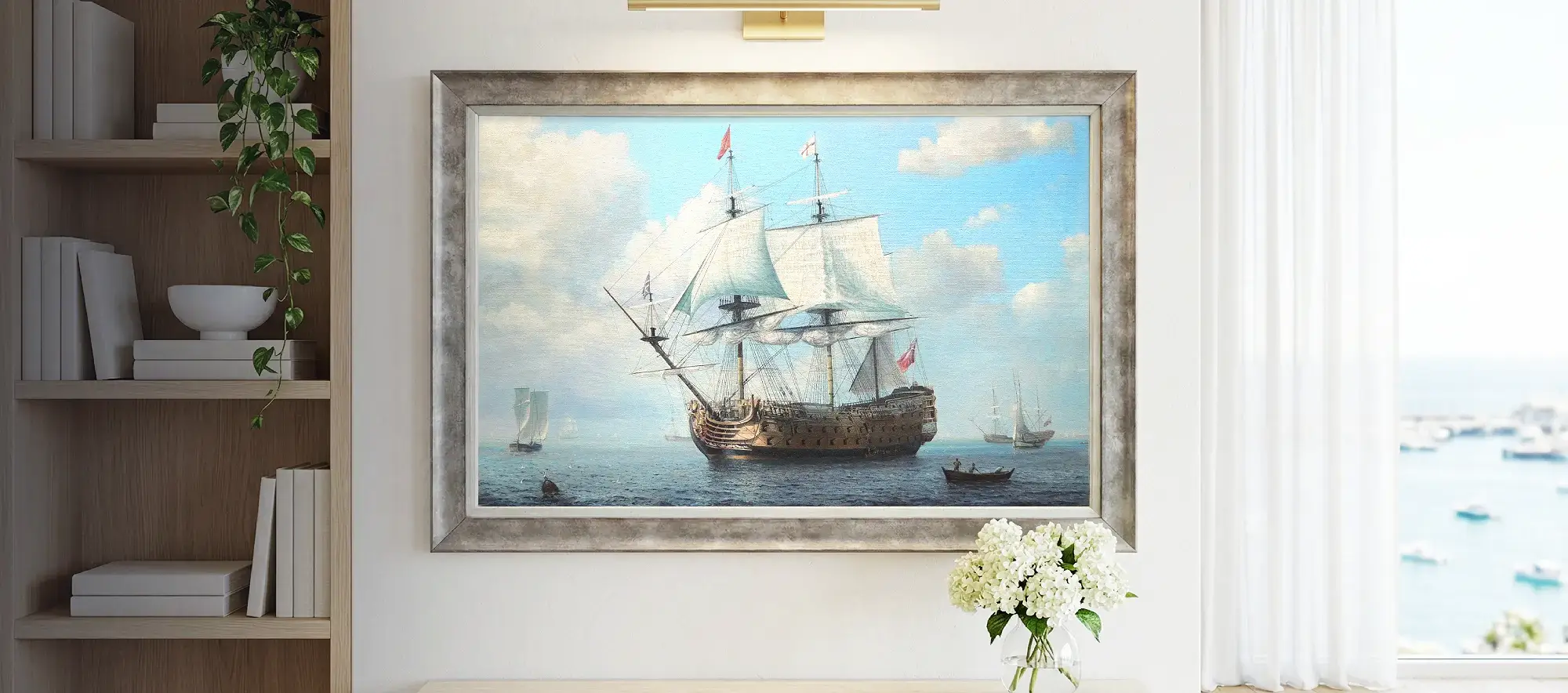 Framed painting of HMS Royal William hanging on a white wall above a light wood console table decorated with white hydrangeas.