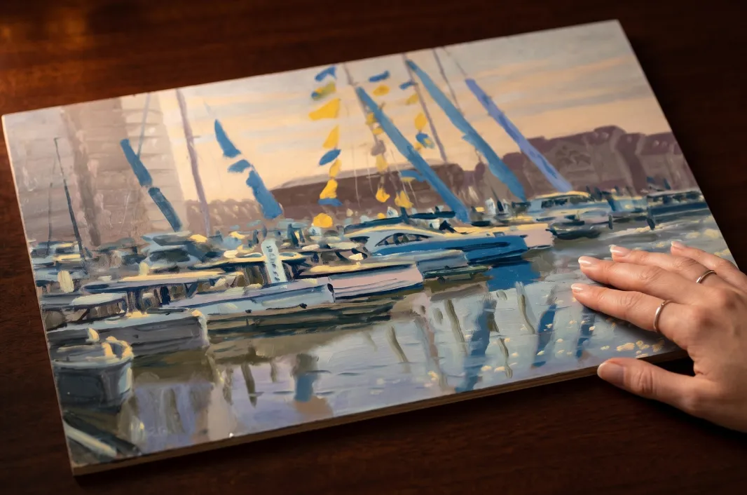 The Saturday Morning oil painting being held against a dark wooden background, showing the scale of the 8x12 inch panel.