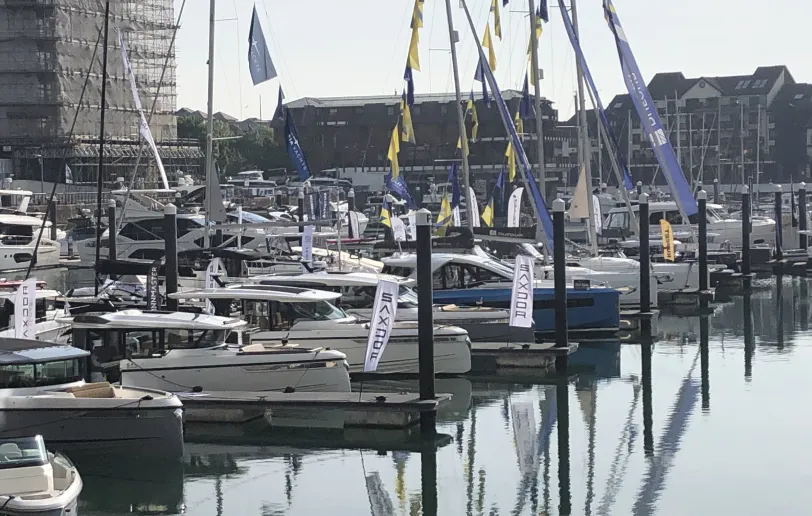Close-up of the left side of the marina showing moored powerboats and the background architecture under a hazy morning sky.