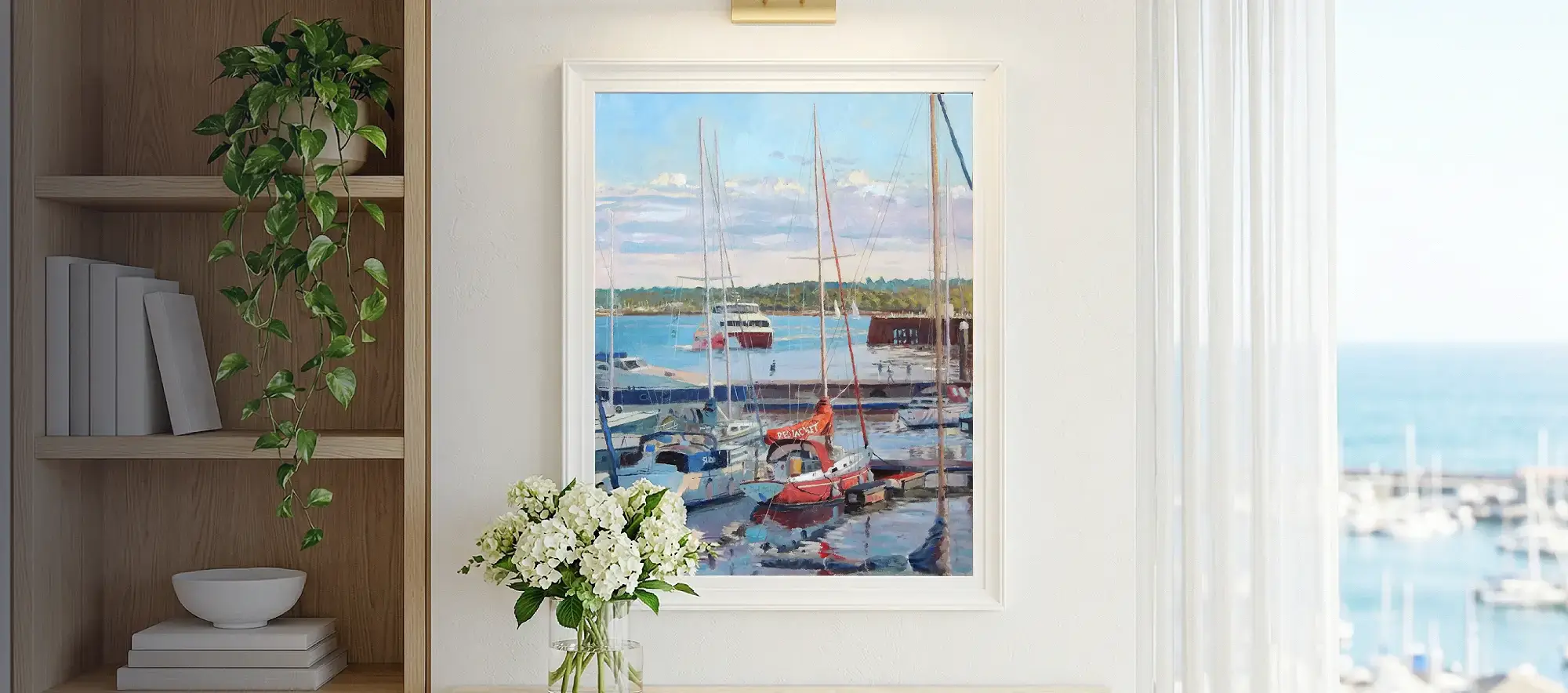Framed portrait-orientation painting of Town Quay hanging on a white wall above a light wood console table decorated with white hydrangeas.