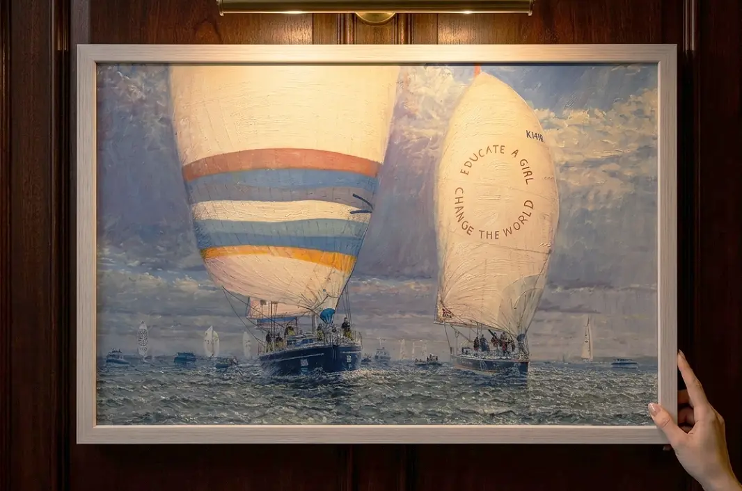 A person's hands adjusting the framed painting against rich dark wooden wall panelling under a warm picture light.