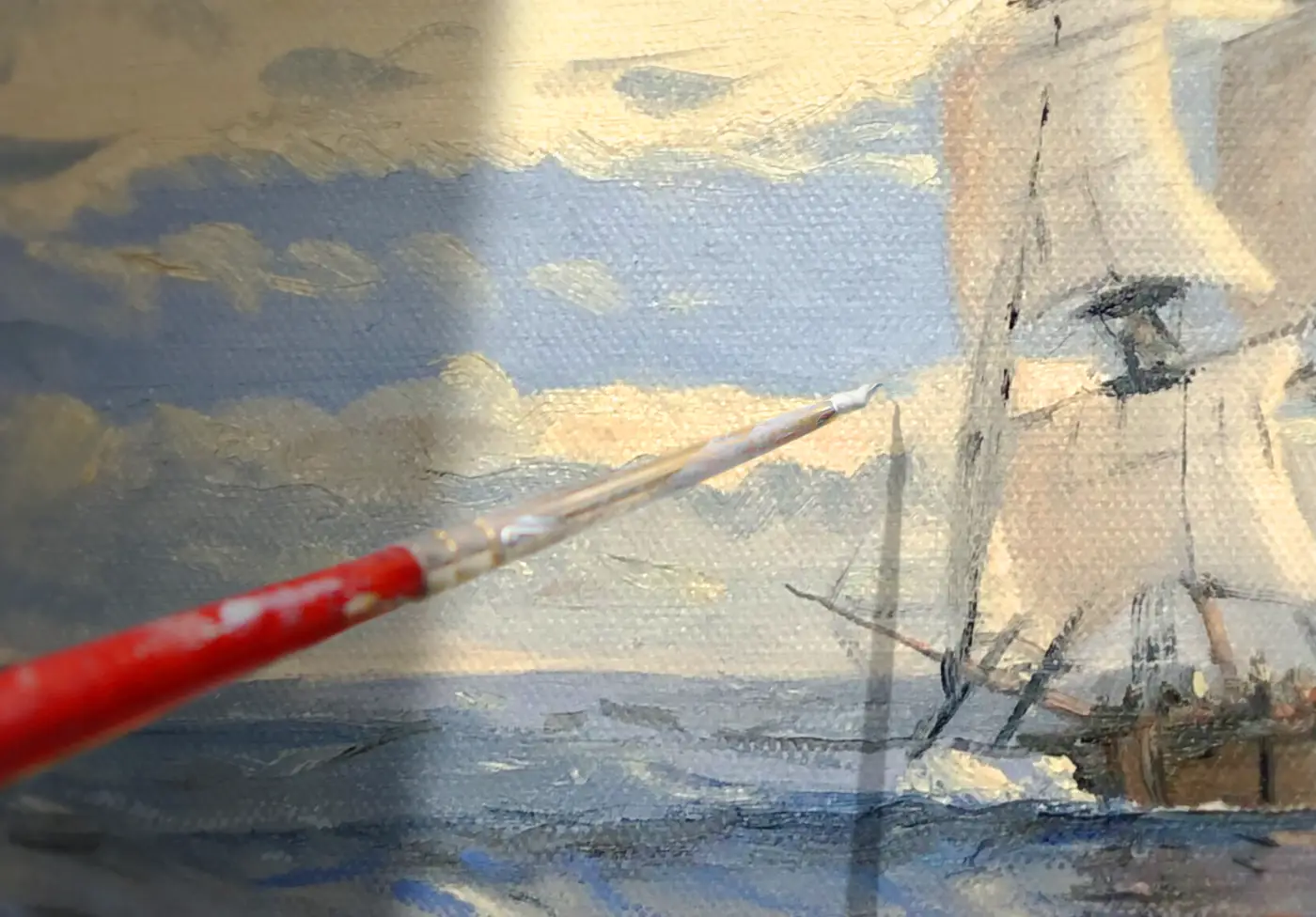 A close-up of the artist's canvas, showing a fine-tipped paintbrush with a red handle adding delicate white paint to the ship's rigging, highlighting the rich texture of the oil paint.
